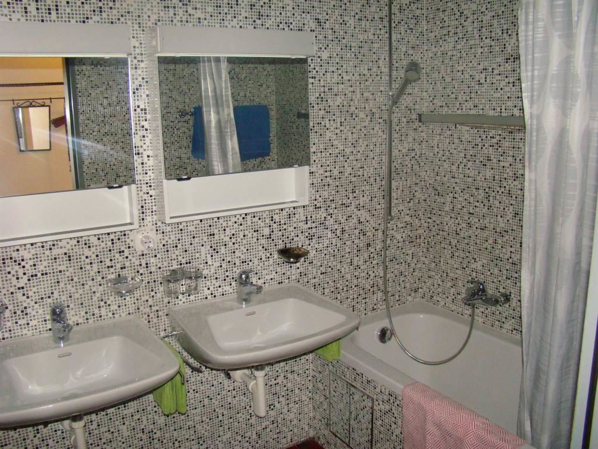 A bathroom with two sinks, a mirror, a shower, and a tiled wall.