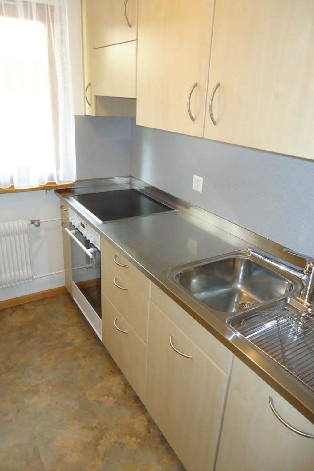 A kitchen with stainless steel appliances, a double sink, and light-colored cabinets.