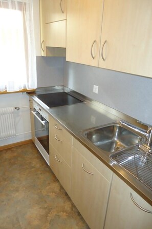 A kitchen with stainless steel appliances, a double sink, and light-colored cabinets. - Haus Rio Appartement/Fewo 5-Bettwohnung Nr. 3 by Interhome (Saas-Fee)