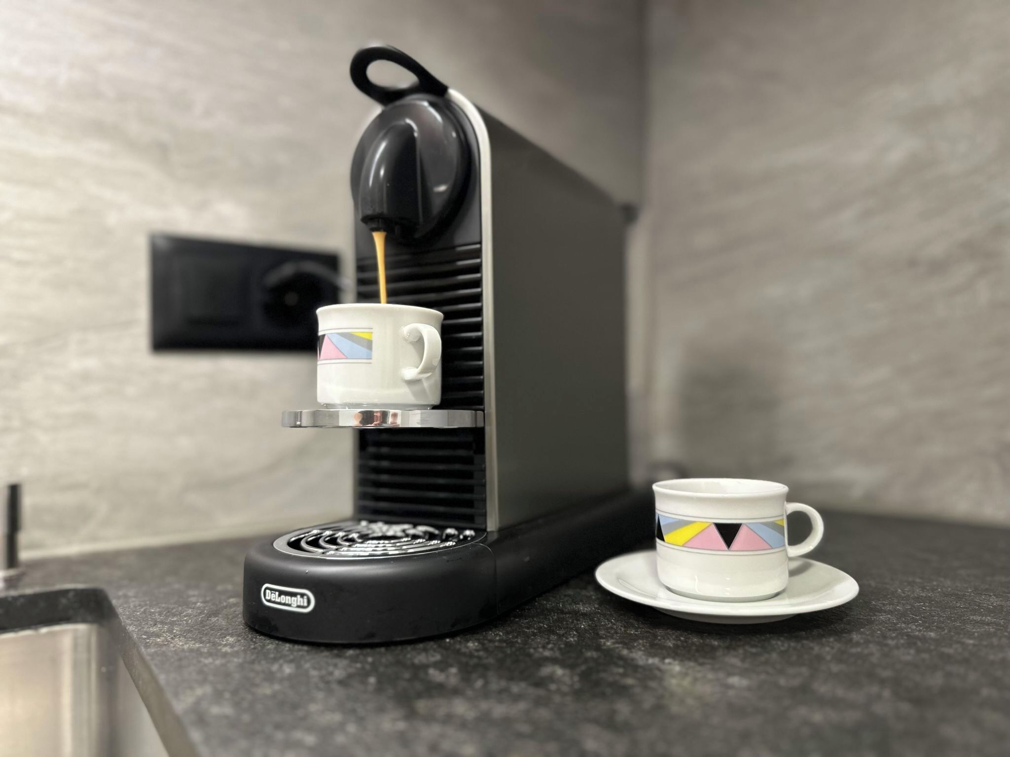 Una máquina de espresso De'Longhi con una taza de café sobre un platito.
