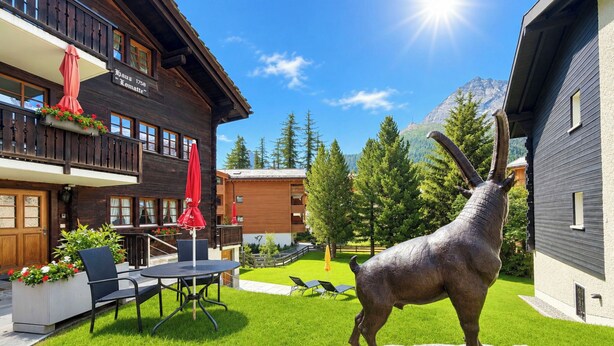 Un bâtiment en bois doté d’un balcon, d’un espace extérieur aménag é pour s’asseoir et offrant une vue sur la montagne.