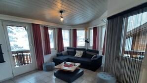 En stue med en hjørnesofa, skammel, sofabord og en loftlampe.