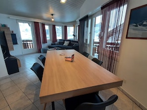 A spacious room with a large wooden table, black chairs, a sofa, and a balcony with a view. - Alpin Smile Appartement/Fewo 6-Bettwohnung 2. Stock by Interhome (Saas-Almagell)