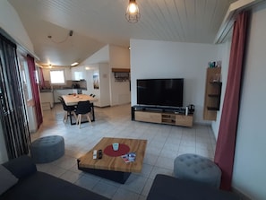 A living room with a TV, a dining area, and a kitchen. - Alpin Smile Appartement/Fewo 6-Bettwohnung 2. Stock by Interhome (Saas-Almagell)