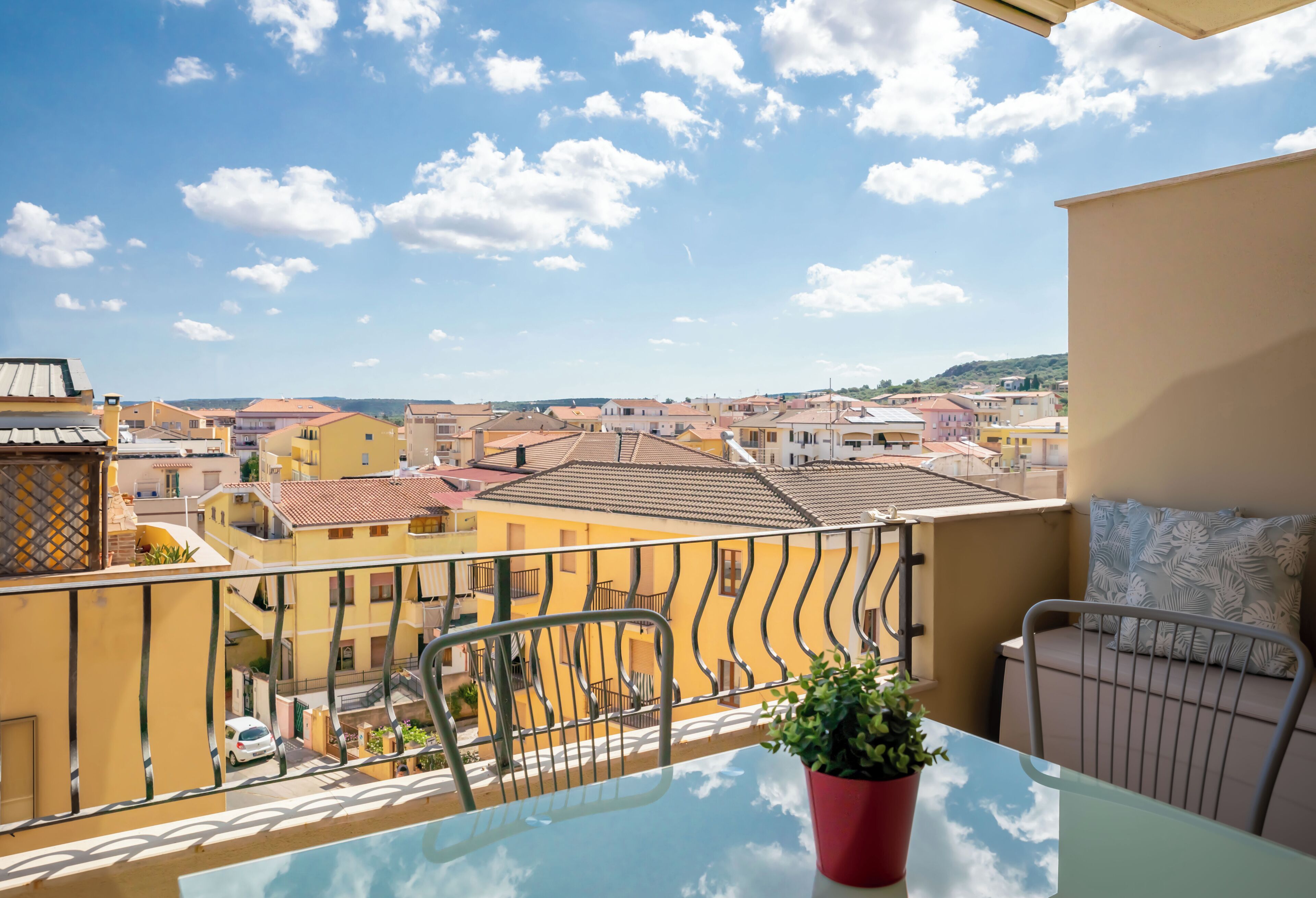 Un balcon avec une table, une chaise et un pot de fleurs.