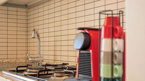 Eine Küche mit einem Gasherd, einem Spülbecken und einem roten Gerät, möglicherweise eine Kaffeemaschine oder ein Durchlauferhitzer.