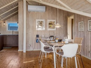 Un comedor con mesa de madera, sillas blancas e iluminación colgante.