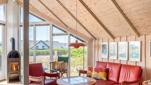 A cozy living room with a fireplace, leather sofa, wooden chairs, and a round table. - "Eldmar" - 500m from the sea by Interhome (Harboøre)