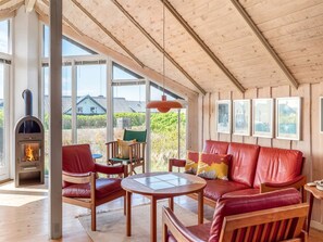 A cozy living room with a fireplace, leather sofa, wooden chairs, and a round table. - "Eldmar" - 500m from the sea by Interhome (Harboøre)