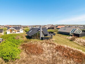 A coastal residential area with modern houses, some with sloped roofs and large windows, surrounded by grassy dunes and a clear sky. - "Eldmar" - 500m from the sea by Interhome (Harboøre)