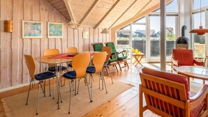 A wooden interior with a dining area, chairs, and a view through large windows. - "Eldmar" - 500m from the sea by Interhome (Harboøre)