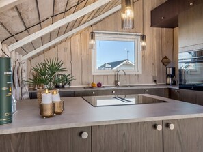 A modern kitchen with a large island, wooden cabinetry, a window with a view, and pendant lighting. - "Eldmar" - 500m from the sea by Interhome (Harboøre)