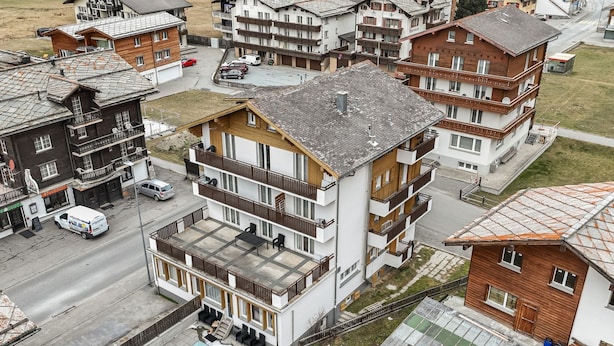 Een meerlaags gebouw met balkons, een terras op de begane grond en uitzicht op de straat.