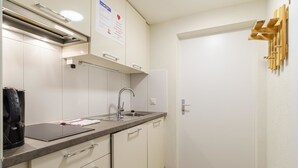 Een kleine keuken met een spoelbak, aanrecht en kastjes.