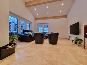 A spacious living area with a high ceiling, large windows, and a flat-screen TV mounted on the wall. - Zum Lerch Appartement/Fewo 8-Bettwohnung by Interhome (Saas-Fee)