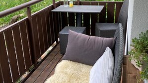 A balcony with a wicker sofa, a small table, and a bottle of water. - Vallesia Appartement/Fewo Appartement/Fewo by Interhome (Saas-Fee)