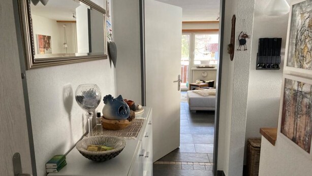 A hallway with a mirror, a bowl with decorative items, and a bed in the background. - Vallesia Appartement/Fewo Appartement/Fewo by Interhome (Saas-Fee)