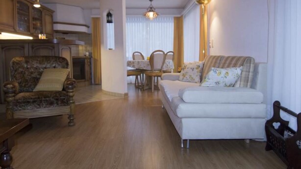 Una sala de estar con sofá, sillón, mesa de comedor y sillas.