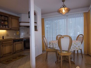 A kitchen with wooden cabinets and a dining area with a table and chairs. - Waldrain 2 Appartement/Fewo 4-Bettwohnung by Interhome (Saas-Fee)