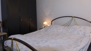 Un dormitorio con cama, armario y mesita de noche con lámpara.