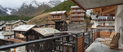 Un balcón con vistas a edificios tradicionales de madera y una montaña al fondo.