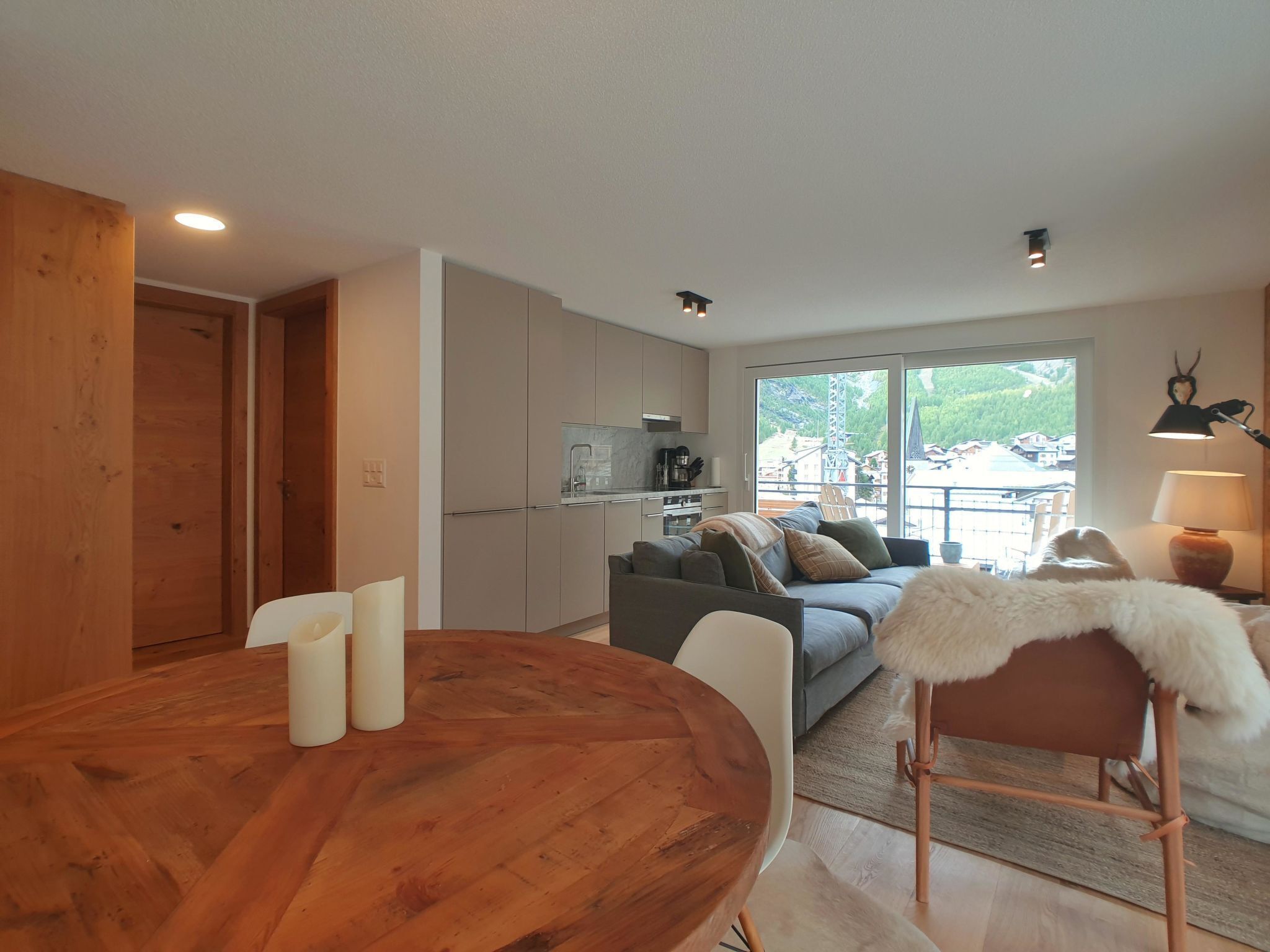 A modern living space with a dining area, kitchen, and a sofa set.