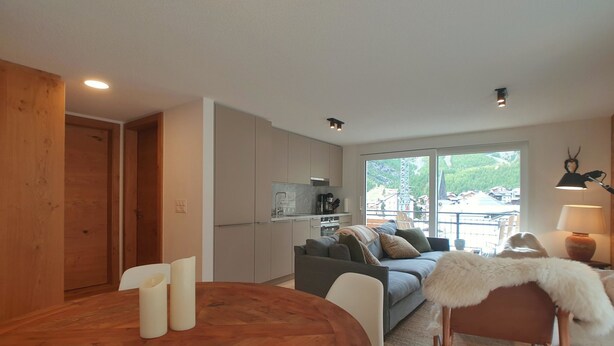 Un espacio habitable moderno con comedor, cocina y un conjunto de sofás.