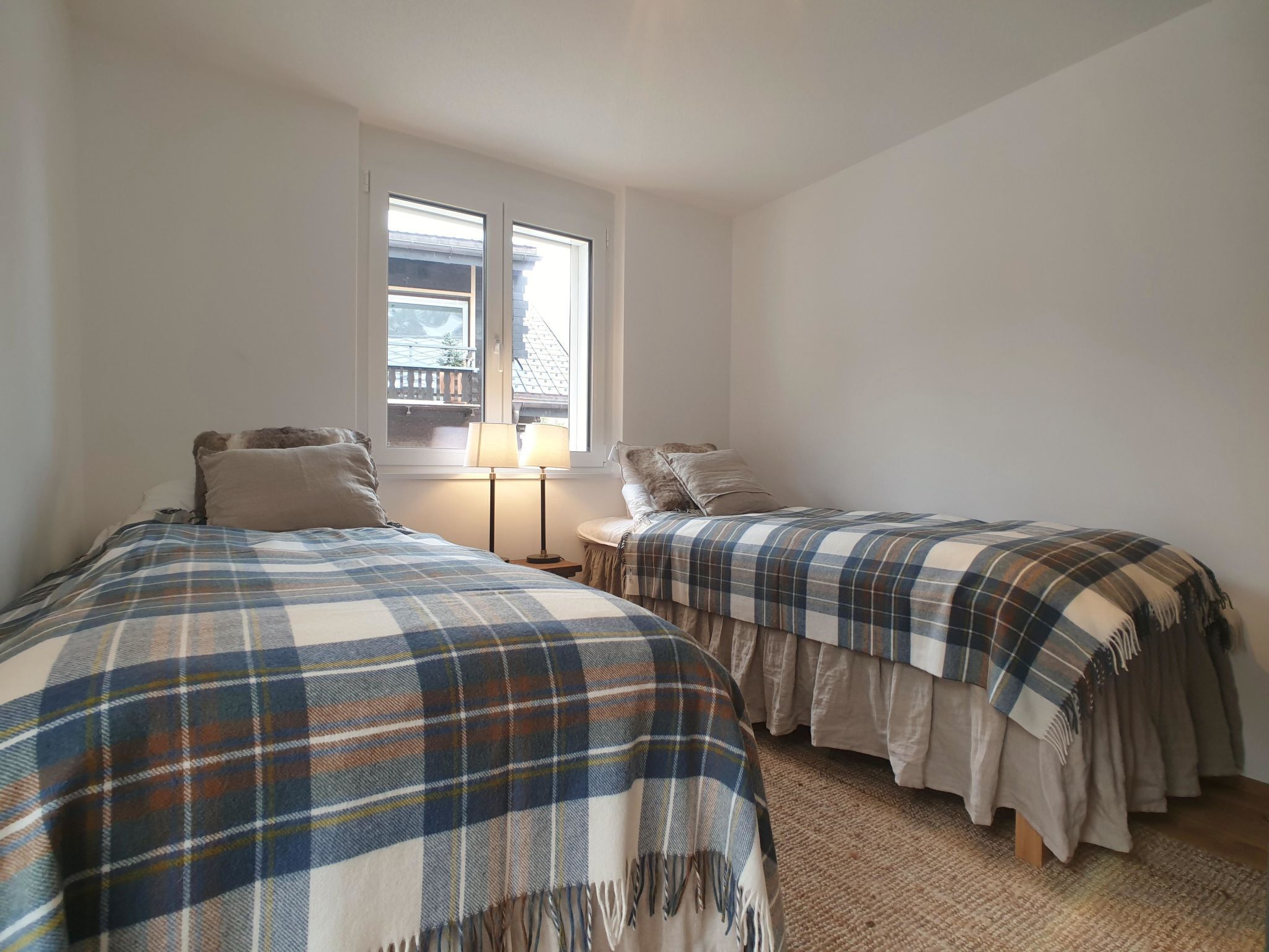 Une chambre avec deux lits, une fenêtre donnant sur un beau paysage et une lampe de chevet.