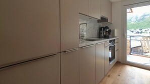 Una cocina moderna con un amplio ventanal, horno empotrado y encimera de mármol.