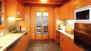 A wooden kitchen with a stone floor, wooden cabinets, a microwave, and a coffee maker. - Les Mélèzes Appartement/Fewo 8-Bettwohnung by Interhome (Saas-Fee)