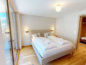 A modern bedroom with a large bed, two bedside lamps, and a view through a glass door. - Alphubel Peak & Unlimited Appartement/Fewo Peak 09 by Interhome (Saas-Fee)