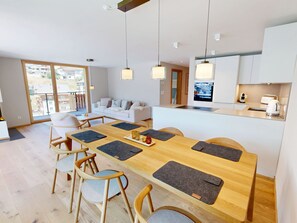 A modern kitchen with a central island, dining area with wooden table and chairs, and a living room with a sofa and chairs. - Alphubel Peak & Unlimited Appartement/Fewo Peak 09 by Interhome (Saas-Fee)