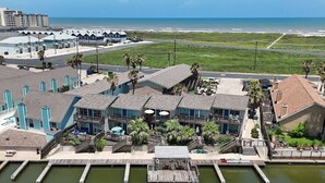 A waterfront hotel with multiple balconies, a dock, and a view of the ocean. - Waterfront Hideaway | Patio, Pool & Fishing Dock (Corpus Christi)