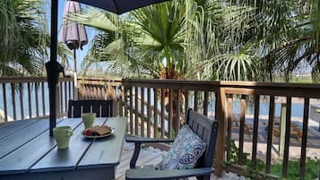 En træterrasse med et bord og stole, en bænk og udsigt til vandet.