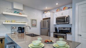 A modern kitchen with a central island, stainless steel appliances, and white cabinetry. - Waterfront Hideaway | Patio, Pool & Fishing Dock (Corpus Christi)