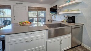 A modern kitchen with white cabinetry, a stainless steel sink, and a coffee maker. - Waterfront Hideaway | Patio, Pool & Fishing Dock (Corpus Christi)