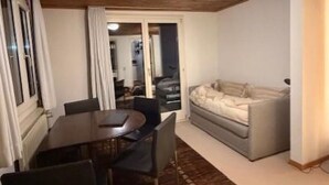 A room with a wooden ceiling, a dining table with chairs, a sofa, and a patterned rug. - Sonnenhang 2 Appartement/Fewo Apartment Nr. 2 by Interhome (Saas-Fee)