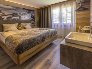A modern hotel room with a large bed, a bathtub, and a scenic wall mural. - Arcade Appartement/Fewo 4-Bettwohnung Nr. 115C06 by Interhome (Saas-Fee)