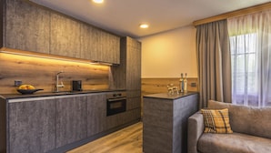 Eine moderne Küche mit Holzausstattung, einem Einbauofen und einem Essbereich mit einer Couch und Vorhängen.