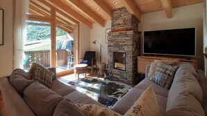 A cozy living room with a stone fireplace, a large flat-screen TV, and a comfortable sofa. - Aramis 5. OG Appartement/Fewo 6-Bettwohnung by Interhome (Saas-Fee)