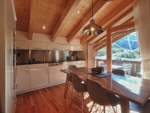 Eine moderne Küche mit Holzbalken, Edelstahlgeräten und einem Essbereich mit Blick ins Freie.