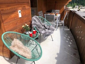 A wooden balcony with wicker chairs, a small table with a vase of flowers, and a view of the surrounding area. - Aramis 5. OG Appartement/Fewo 6-Bettwohnung by Interhome (Saas-Fee)
