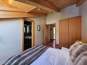 Ein Schlafzimmer mit Bett, Kleiderschrank, Spiegel und einer Tür zu einem Badezimmer.