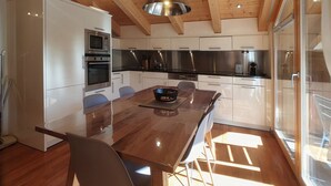 A modern kitchen with wooden beams, stainless steel appliances, and a large dining table. - Aramis 5. OG Appartement/Fewo 6-Bettwohnung by Interhome (Saas-Fee)