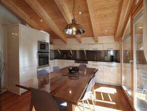 A modern kitchen with wooden beams, stainless steel appliances, and a large dining table. - Aramis 5. OG Appartement/Fewo 6-Bettwohnung by Interhome (Saas-Fee)