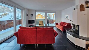 Una sala de estar moderna con un sofá rojo, una televisión y una chimenea.