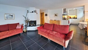 Una sala de estar con dos sofás rojos, una chimenea y una cocina al fondo.