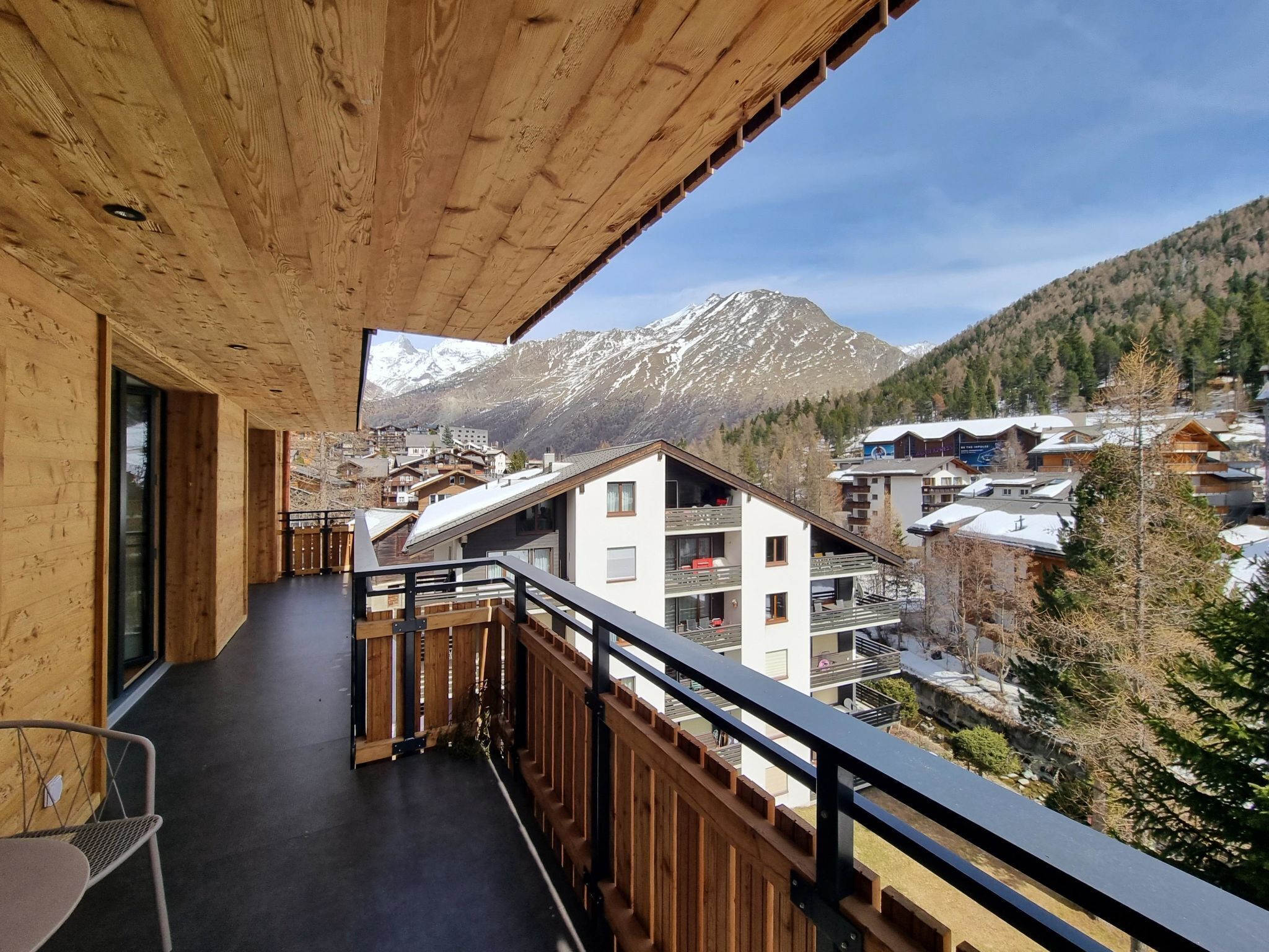 Ein Balkon mit Blick auf schneebedeckte Berge und eine darunterliegende Stadt.