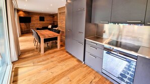 Eine moderne Küche mit grauen Schränken, einem Holzespeisetisch und einem eingebauten Backofen.