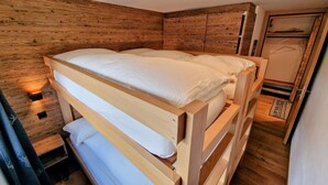 Ein Etagenbett mit Holzkopfteil und einem kleinen Nachttisch mit Lampe.